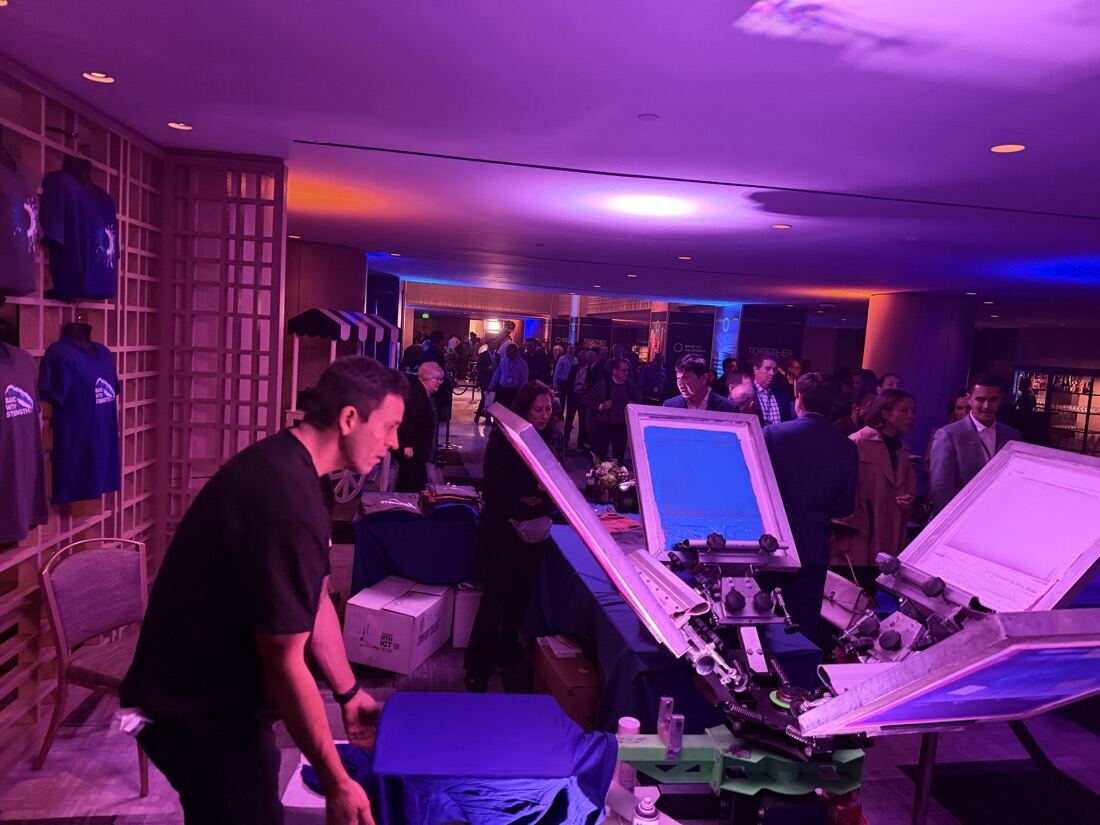 Print stations set up in a purple-lit lounge full of party guests