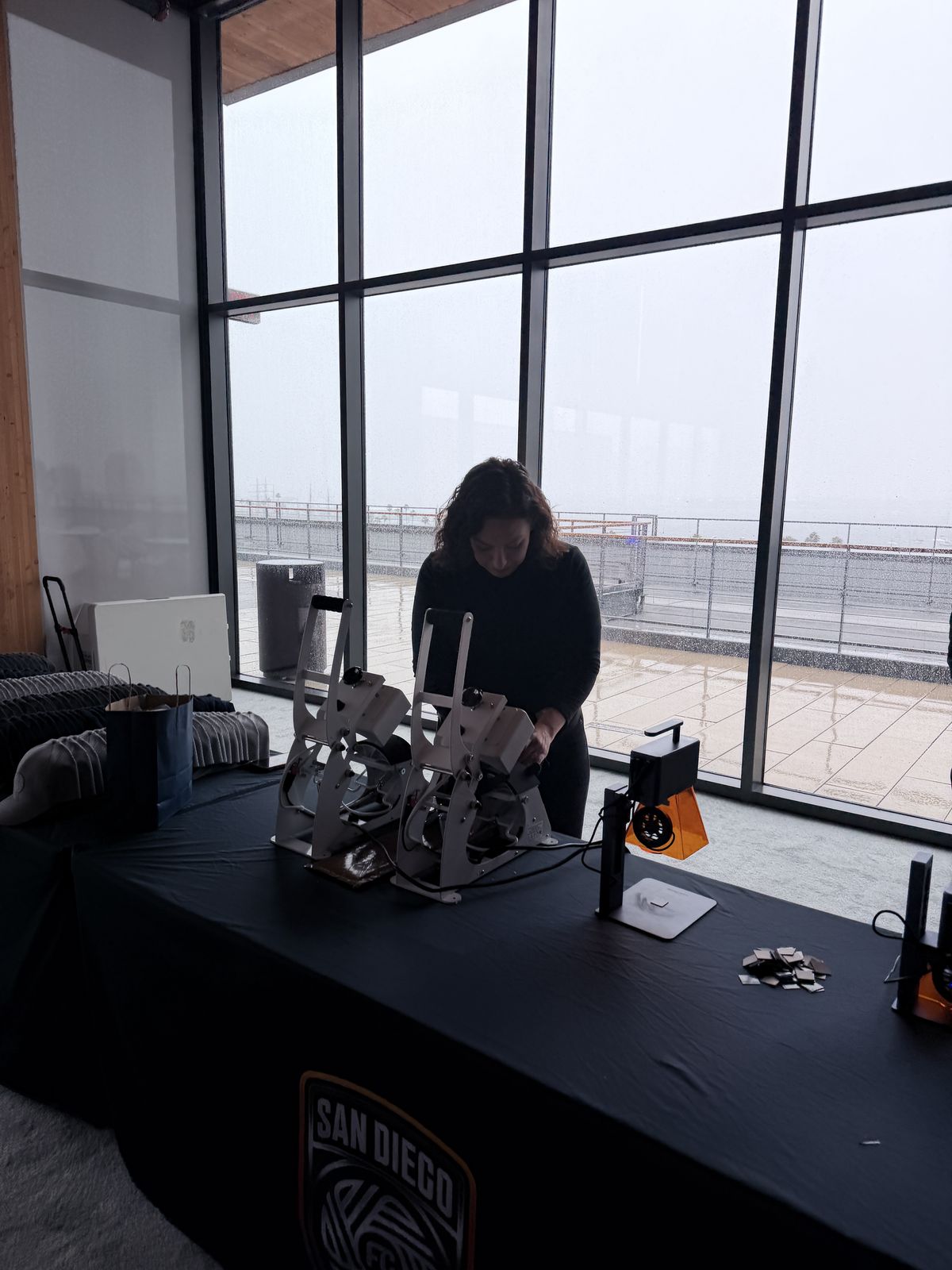 Heat presses and engraver staged on a table in front of floor-to-ceiling windows